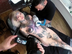 Sascha plays with Amber Luke while she gets tattooed